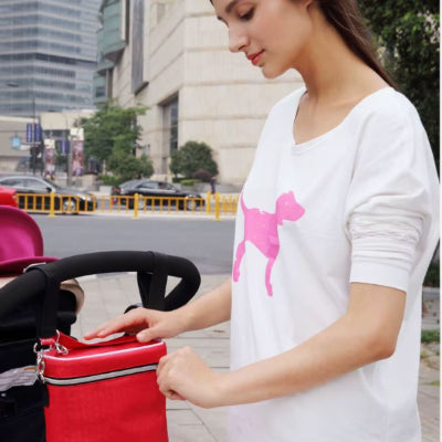 Sac isotherme Bebe rouge en cours dâouverture par une jeune maman, dĂ©monstration de lâaccĂšs rapide et facile au contenu pour nourrir bĂ©bĂ© sans stress.