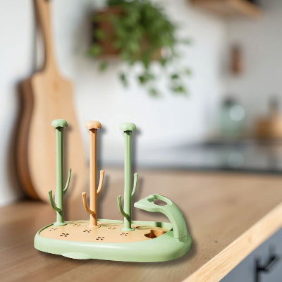 Support de séchage CompactBébé™ en version verte et orange pastel, présenté sur un comptoir de cuisine contemporaine, idéal pour le rangement hygiénique des biberons et accessoires dans un espace familial.