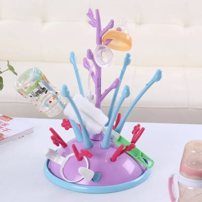 Sèche biberon coloré rempli de biberons, tétines et goupillons sur un meuble blanc, pratique pour une organisation de biberonnerie efficace.