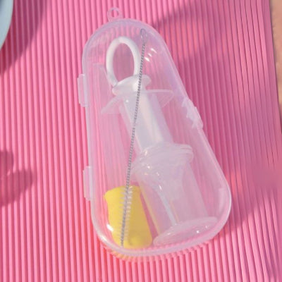Seringue d'alimentation orale avec tétine blanche et embout jaune, dans un boîtier transparent avec un pinceau de nettoyage.
