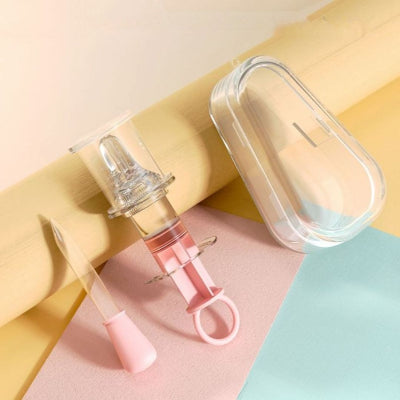 Seringue d'alimentation orale rose et jaune avec embout souple, dans un boîtier transparent pour un rangement pratique et sécurisé.