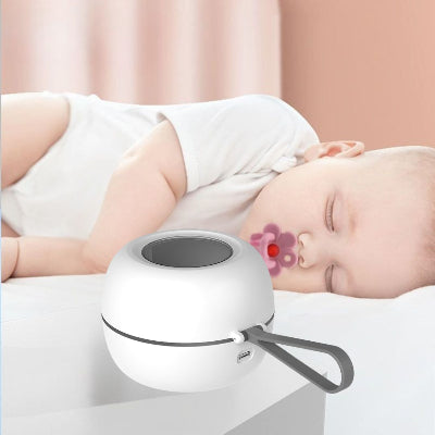 Stérilisateur tétine posé sur une table de nuit à côté d’un bébé endormi avec tétine, illustrant l’usage nocturne silencieux et sécuritaire pour une hygiène continue même la nuit.