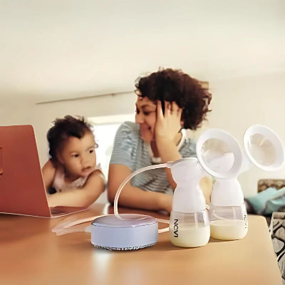 Tire-lait électrique utilisé par une maman travaillant sur son ordinateur, illustrant la praticité et la discrétion du produit.