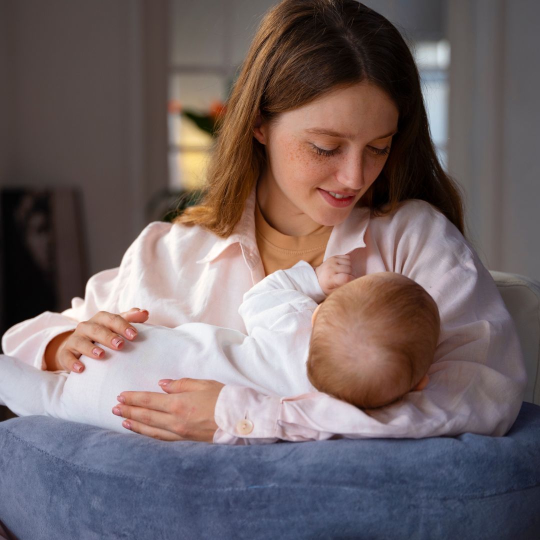 Maman allaitant tendrement son bébé avec un coussin de soutien ergonomique – moment de complicité et confort pendant l’allaitement maternel.