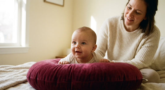 bébé de 3 mois en tummy time posé sur un coussin d'allaitement bordeaux, éveil et renforcement musculaire`