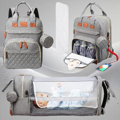 Sac à dos à langer LuxeNest™ Gray Charm avec des fonctionnalités innovantes telles qu'un lit pliable intégré, des poches isothermes et un design élégant en gris.