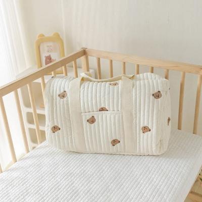 Le sac à langer DreamNest™ Teddy Charm placé sur un lit d’enfant, arborant de charmants motifs d’oursons, idéal pour des parents cherchant une touche de douceur et de praticité.