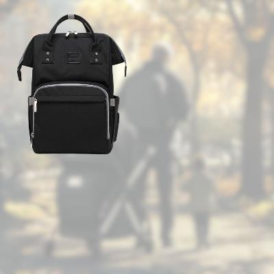 Sac à langer SerenityPack™ noir, conçu pour des parents dynamiques en déplacement, avec une scène floue d'une balade familiale.