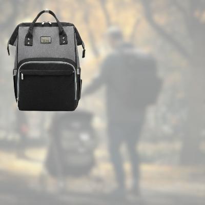 Sac à langer SerenityPack™ gris et noir, parfait pour une journée en parc avec papa et bébé, dans une atmosphère automnale