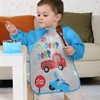 Bébé concentré portant un bavoir à manche longue bleu avec motifs voiture et camion, parfait comme bavoir bébé naissance imperméable pour les repas salissants.