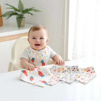 Bébé en chaise haute avec plusieurs bavoirs bandana en coton