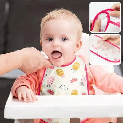 Bébé souriant portant un bavoir bébé imperméable motif ananas pendant le repas
