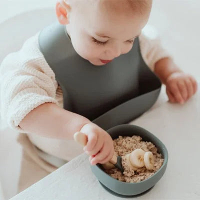 Bavoir bébé imperméable en silicone pendant un repas autonome avec céréales