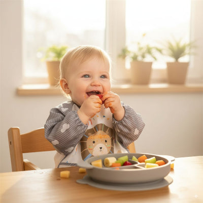 Bavoir bébé manche longue motif lion utilisé comme blouse bébé repas, offrant une protection complète pendant que l’enfant mange des fruits en autonomie.