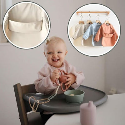 Bébé blond souriant en chaise haute portant un bavoir bébé manche longue rose poudré, avec illustrations zoom sur la poche récupératrice et les coloris disponibles.