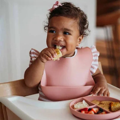 Bavoir bébé en silicone rose avec poche récupératrice pendant la diversification alimentaire