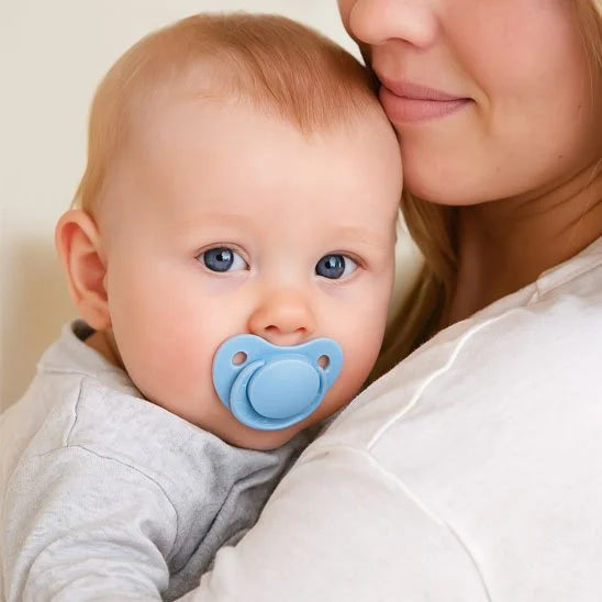 Bébé apaisé dans les bras de sa maman avec une tétine bleue en silicone, moment de tendresse et de sécurité
