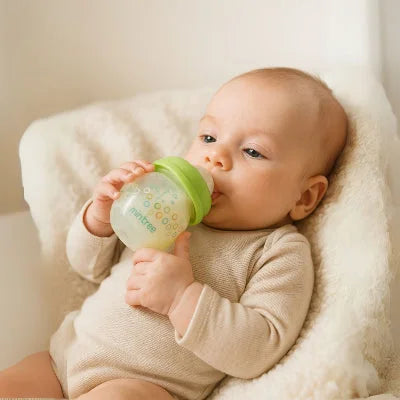 Bébé nourri avec un biberon pour nouveau-né vert à tétine physiologique et débit lent.