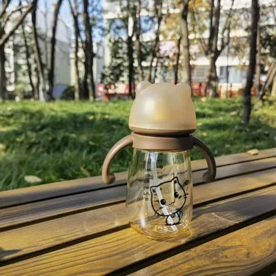 Biberon en PPSU à motif chat posé sur un banc en plein air, résistant aux chocs et facile à emporter.

