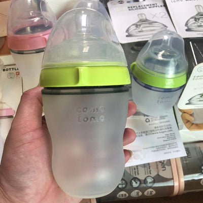 Biberon Como Tomo vert citron 250 ml tenu en main, silicone souple, tétine physiologique anti-colique, idéal pour les parents actifs.