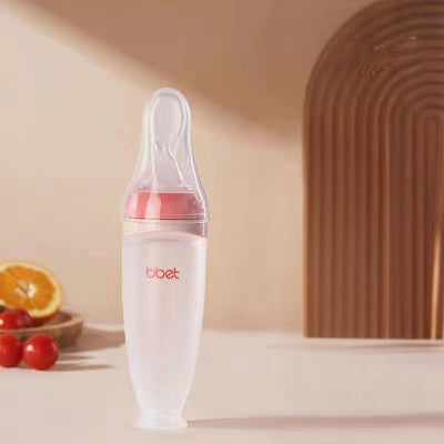 Biberon cuillère rouge présenté avec ses bouchons anti-fuite et filtre à trous offerts.