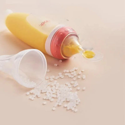 Biberon cuillère rouge couché sur la table avec silicone souple et perles alimentaires.