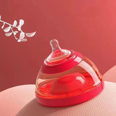 Biberon en forme de sein avec base rouge posé sur une surface douce, ambiance chaleureuse.