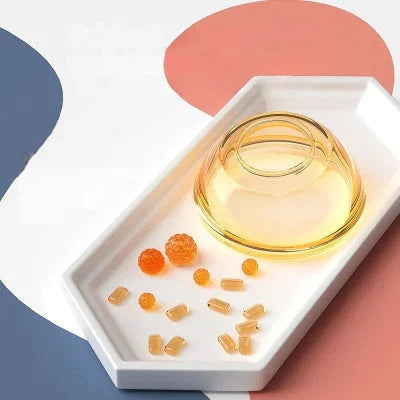 Base du biberon en forme de sein en PPSU transparent, sur plateau blanc avec billes colorées.