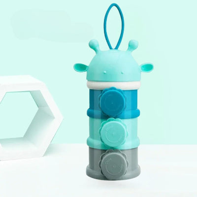 Boite doseuse lait en forme de girafe bleue avec trois compartiments et bouchons latéraux, parfaite pour stocker lait, snacks et accessoires bébé.

