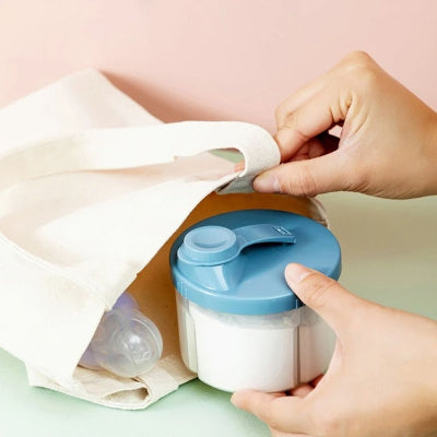  Boite doseuse lait glissée dans un tote bag, prête pour les sorties avec bébé, avec tétine visible à côté pour une utilisation complète.