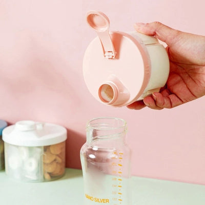 Versement facile de lait infantile depuis une boite doseuse lait rose dans un biberon, avec ouverture en entonnoir pour éviter les débordements.