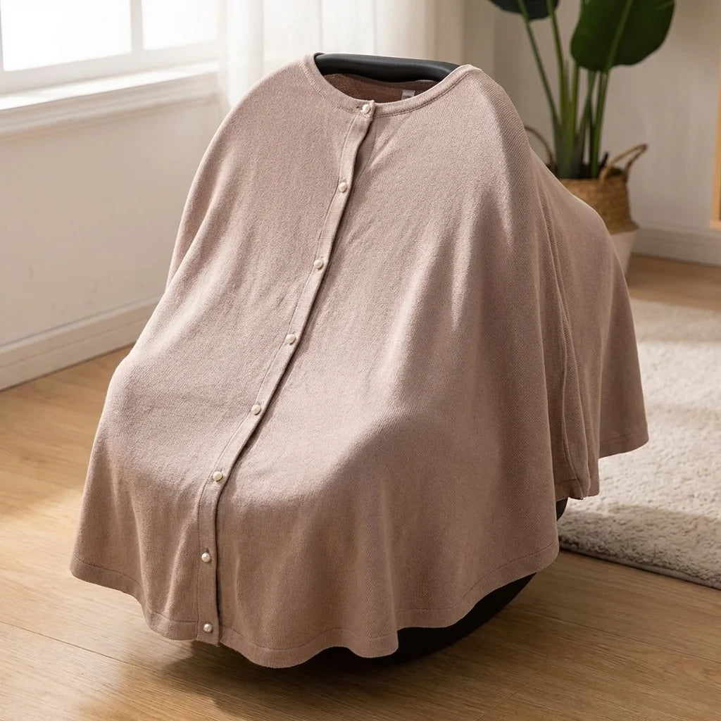 Cape pour allaitement Solène beige taupe utilisée en couverture siège auto sur parquet, intérieur lumineux avec plante verte