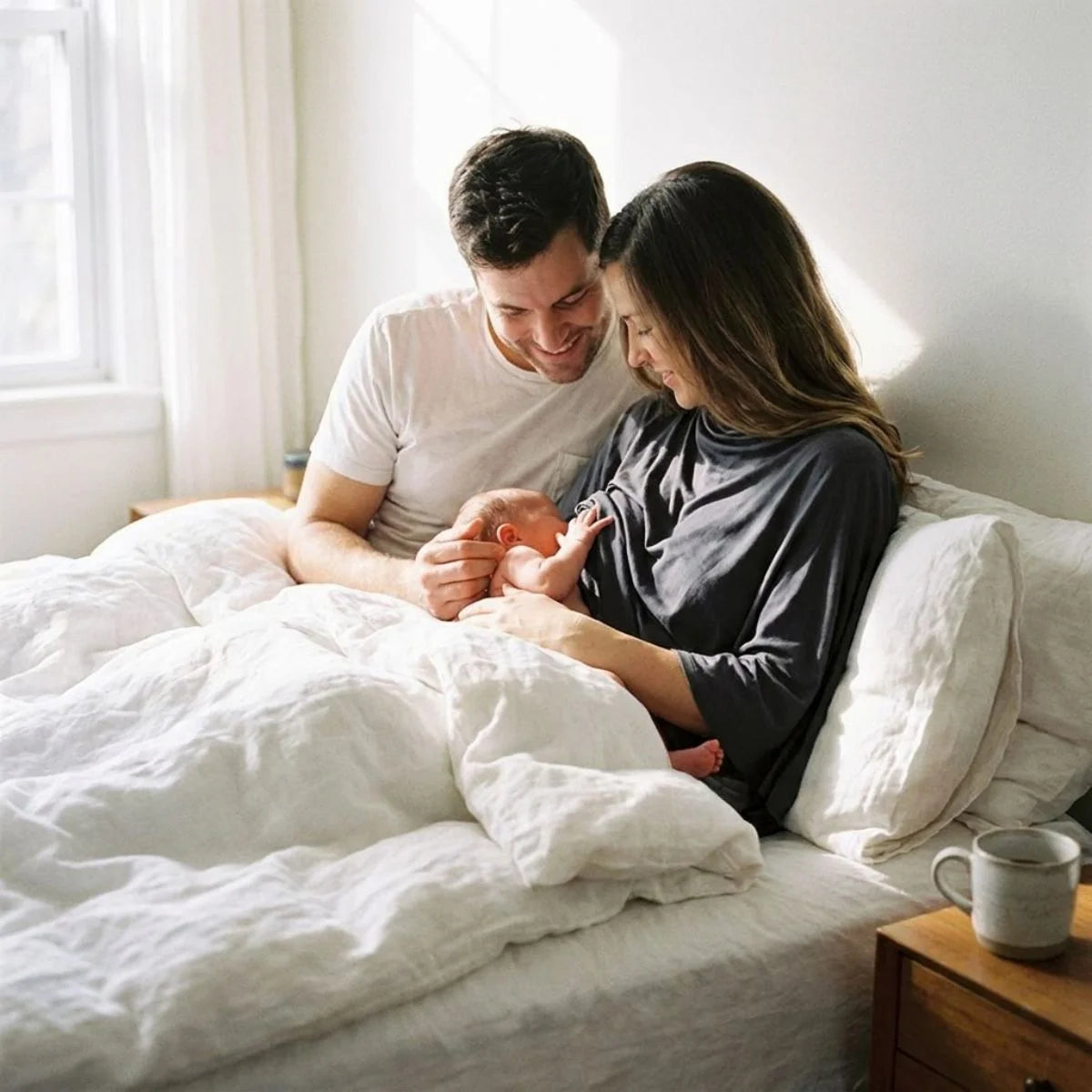 Cape allaitement Solène™ gris — parents et nouveau-né réunis dans une chambre lumineuse, douceur post-partum