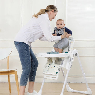 Chaise haute bébé évolutive réglable en hauteur, maman installe son enfant en toute sécurité pour faciliter les repas quotidiens.