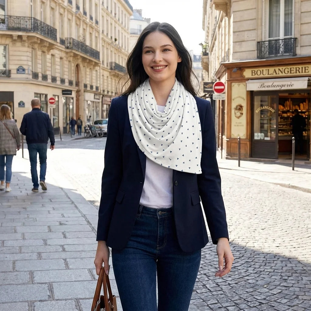 Châle allaitement DouxVoile™ Géo blanc triangles porté en foulard élégant rue parisienne pavée — usage quotidien boulangerie fond