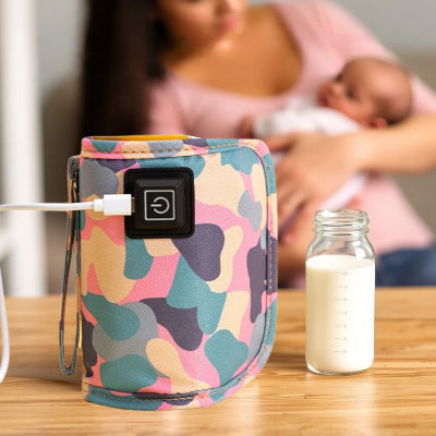 Chauffe biberon nomade camouflage utilisé sur une table avec un biberon de lait et une maman tenant son bébé, illustrant une solution pratique et discrète pour la maison.