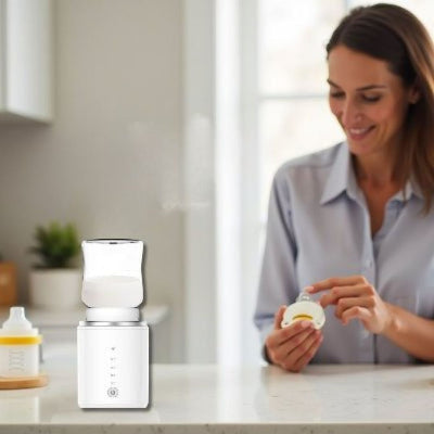 Chauffe biberon ThermoWarm Pro blanc posé sur le plan de travail pendant que la maman prépare une tétine.