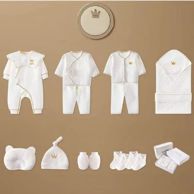 Illustration des différentes pièces du coffret naissance bébé Nanaël™ incluant pyjamas, oreiller, bonnet, moufles, chaussettes et boîte.