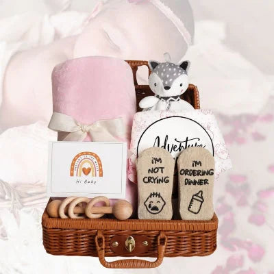 Coffret naissance bébé en version fille, devant une silhouette de bébé endormie, ambiance douce avec fond rose et pétales décoratifs.