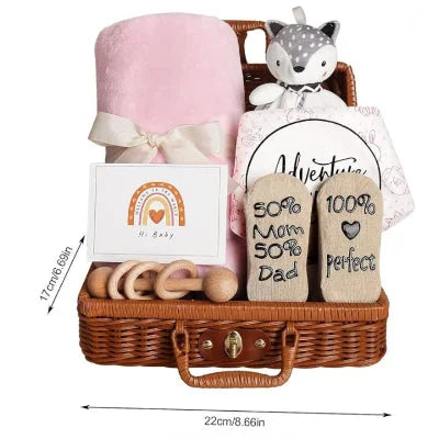 Coffret naissance bébé rose mesurant 22 x 17 cm, présenté avec une couverture douce, un hochet en bois, un doudou renard et des chaussettes imprimées dans un panier en osier.

