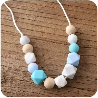 Collier d’allaitement silicone bleu pastel et perles en bois naturel, parfait pour apaiser les gencives et garder bébé concentré lors du portage ou des câlins.

