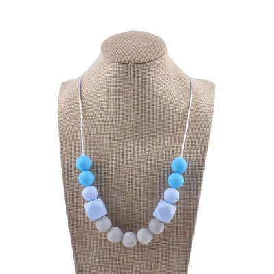 Collier d’allaitement bleu ciel et blanc en silicone alimentaire, conçu pour apaiser les gencives et canaliser l’attention pendant l’allaitement.