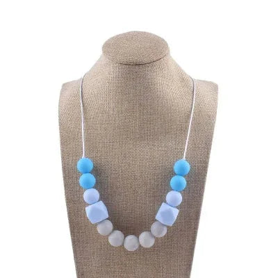 Collier d’allaitement bleu ciel et blanc en silicone alimentaire, conçu pour apaiser les gencives et canaliser l’attention pendant l’allaitement.