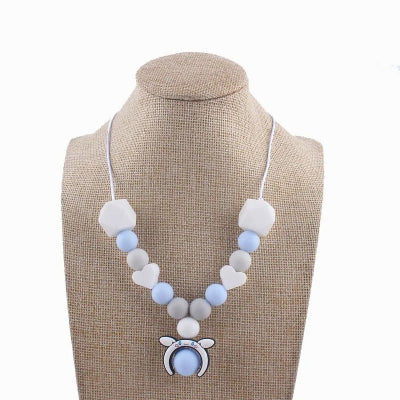 Collier d'allaitement bleu et gris avec perles en silicone et pendentif ourson, conçu pour stimuler les sens de bébé et soulager les poussées dentaires.