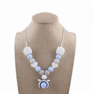 Collier d'allaitement bleu et gris avec perles en silicone et pendentif ourson, conçu pour stimuler les sens de bébé et soulager les poussées dentaires.