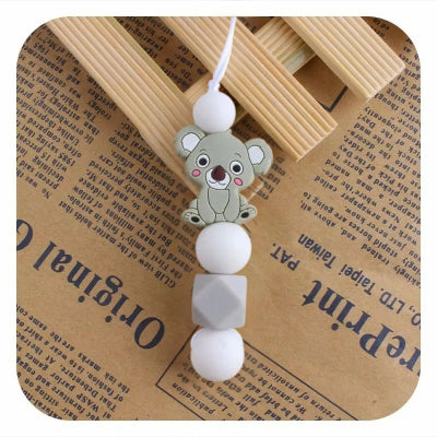 Collier d’allaitement gris avec pendentif koala et perles blanches, pour apaiser les poussées dentaires tout en gardant un look naturel et sobre.