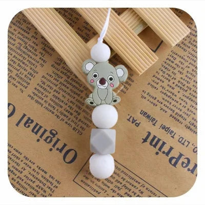 Collier d’allaitement gris avec pendentif koala et perles blanches, pour apaiser les poussées dentaires tout en gardant un look naturel et sobre.