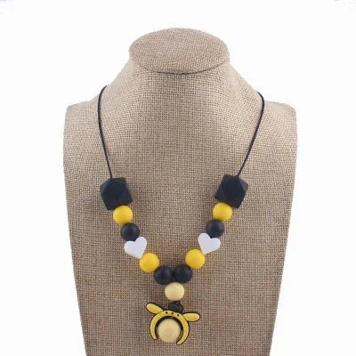 Collier d’allaitement noir et jaune avec pendentif abeille, perles contrastées et coeurs blancs, idéal pour stimuler la vue et soulager les gencives.