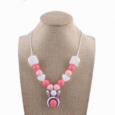 Collier d'allaitement en silicone rose avec perles en forme de cœur et pendentif lapin, idéal pour apaiser bébé tout en ajoutant une touche mignonne.
