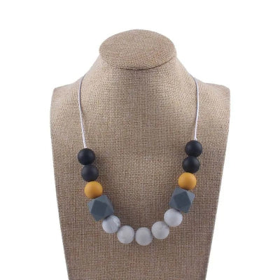Collier d’allaitement en silicone noir, moutarde et gris, idéal pour soulager les poussées dentaires et stimuler la motricité fine de bébé